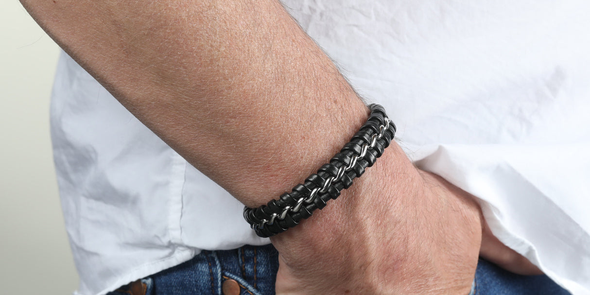 Schwarzes geflochtenes Lederarmband mit Edelstahl-Elementen am Handgelenk getragen