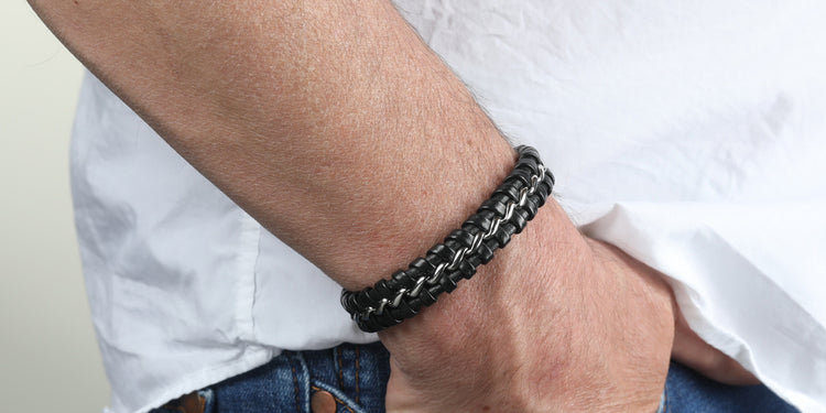 Schwarzes geflochtenes Lederarmband mit Edelstahl-Elementen am Handgelenk getragen