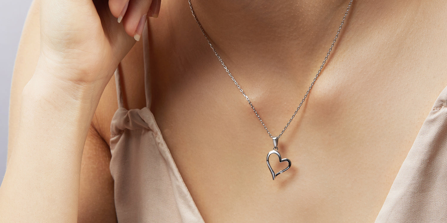 Silberne Halskette mit Herzanhänger am Dekolleté getragen